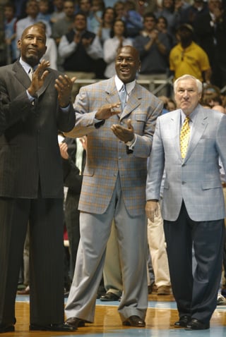 North Caroline Tar Heels alum James Worthy and Michael Jordan and retired Coach Dean Smith are pictured at a UNC men's basketball game honoring the 1957 and 1982 championship teams.  Photo by Zeke Smith from Chapel Hill, North Carolina [CC BY-SA 2.0 (creativecommons.org/licenses/by-sa/2.0)] via Wikimedia Commons