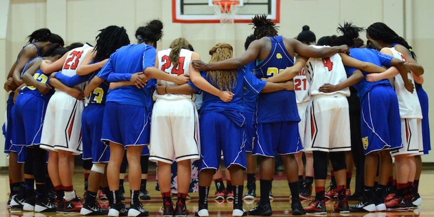 Union University's women's basketball team prays with an opposing team after a game. The college is located in Jackson, Tennessee.